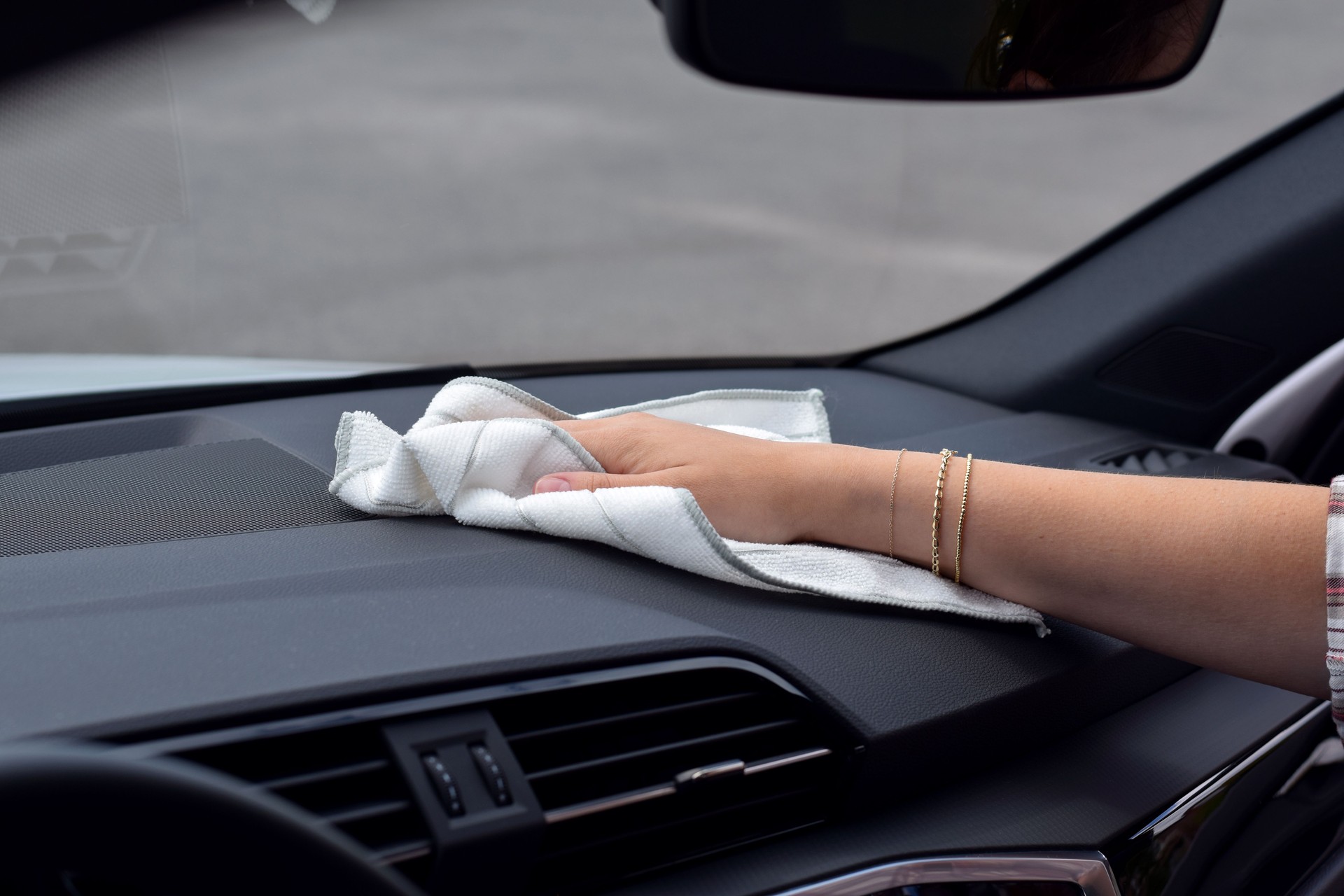 Hand of a woman cleaning car dashboard